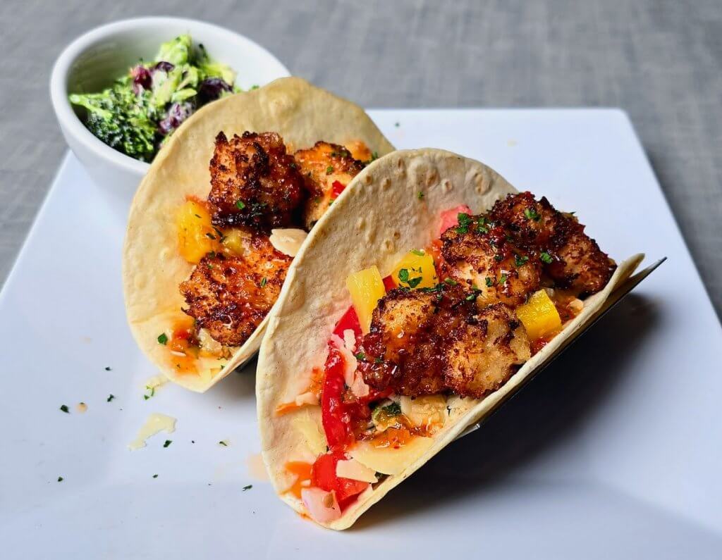 Coconut Crusted Scallop Tacos – Crispy coconut-crusted scallops in flour tortillas with Baja slaw, salsa fresca, shaved Parmesan, and diced pineapple. 