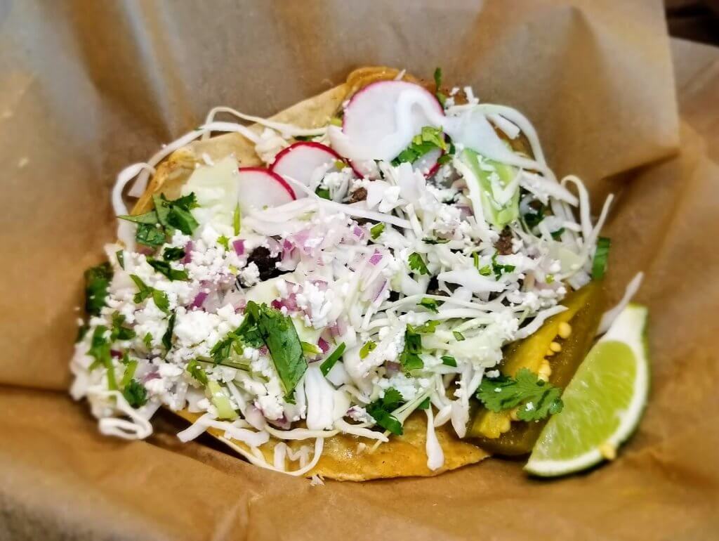 Choice of protein on a 100% corn tortilla with shaved cabbage, cotija cheese, radish, onion, cilantro, and julienned sweet peppers.