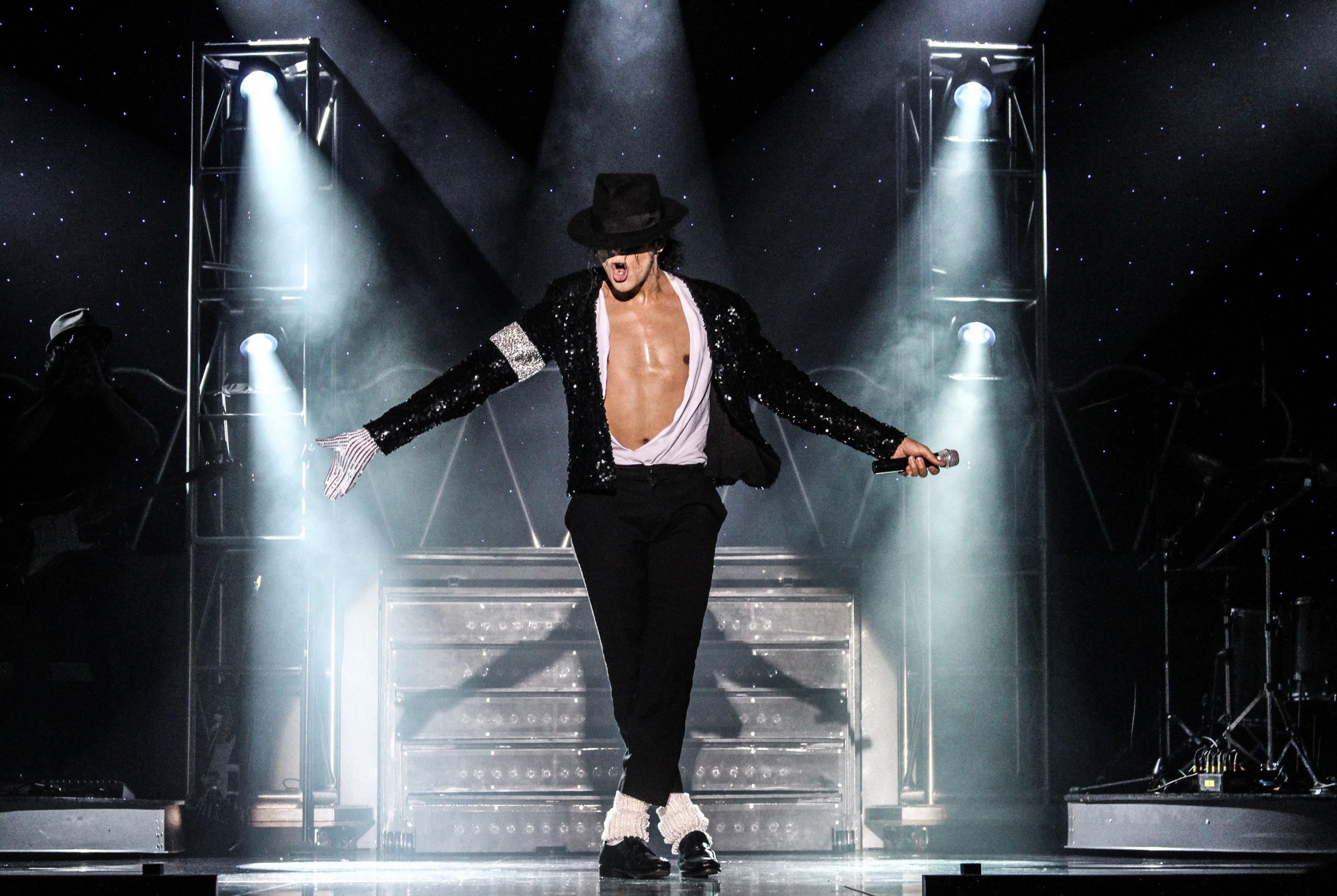 A Michael Jackson lookalike performs on stage with a tribute band