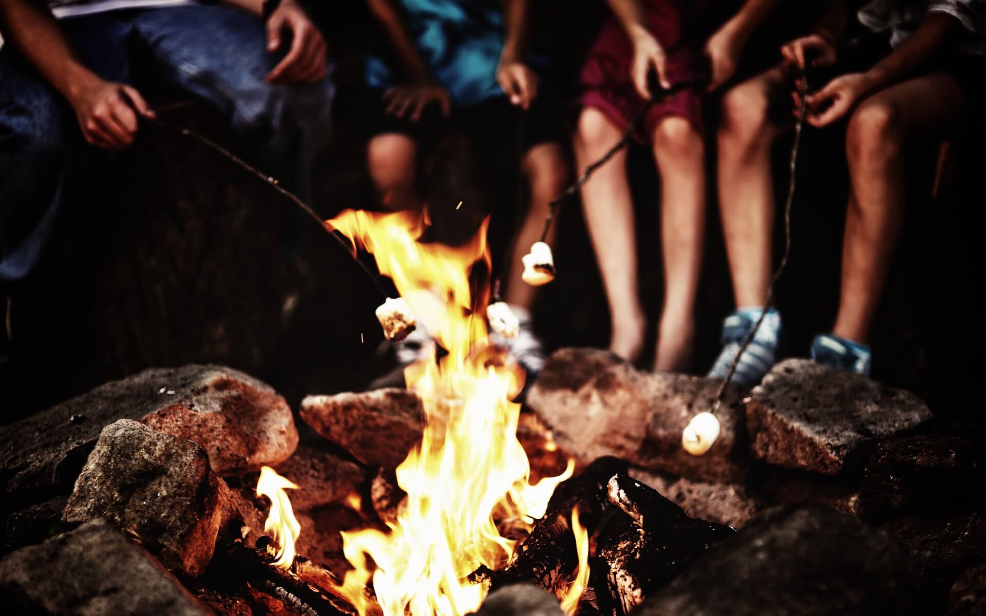 Family gathered around a campfire roasting marshmellows